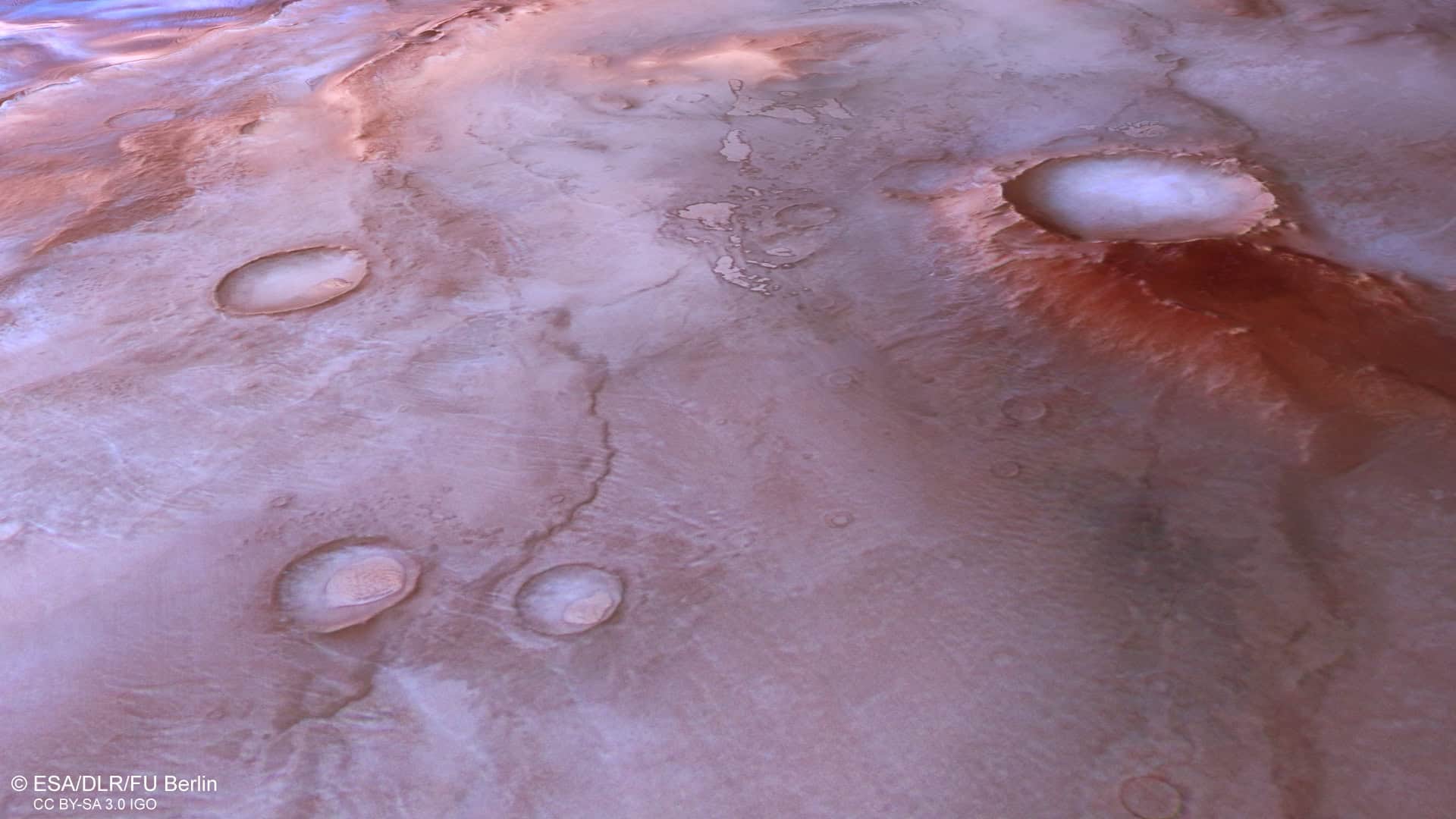 Vista aérea da região de Thyles Rupes, no sul de Marte, com crateras, áreas avermelhadas e depósitos de gelo na superfície