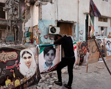 Masoud bows his head against a memorial banner for his son amid the school's rubble