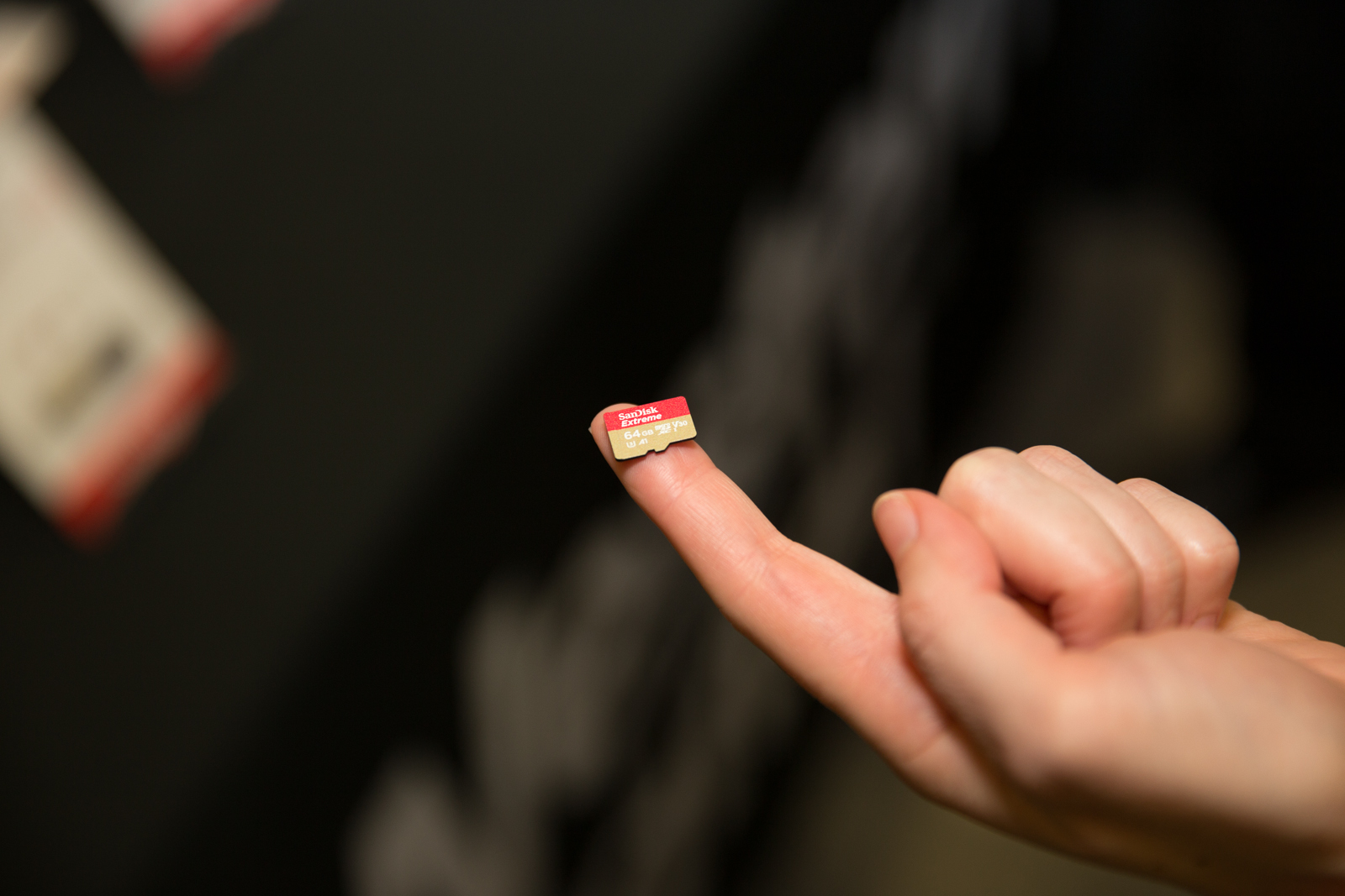 A hand holds a microSD card on its finger.