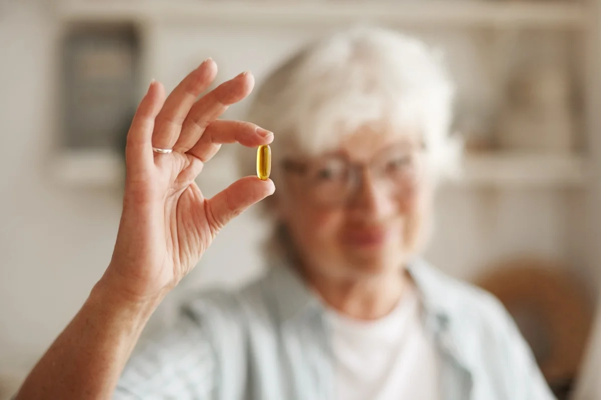 Imagem de uma idosa segurando uma pílula de vitamina b12 - Metrópoles